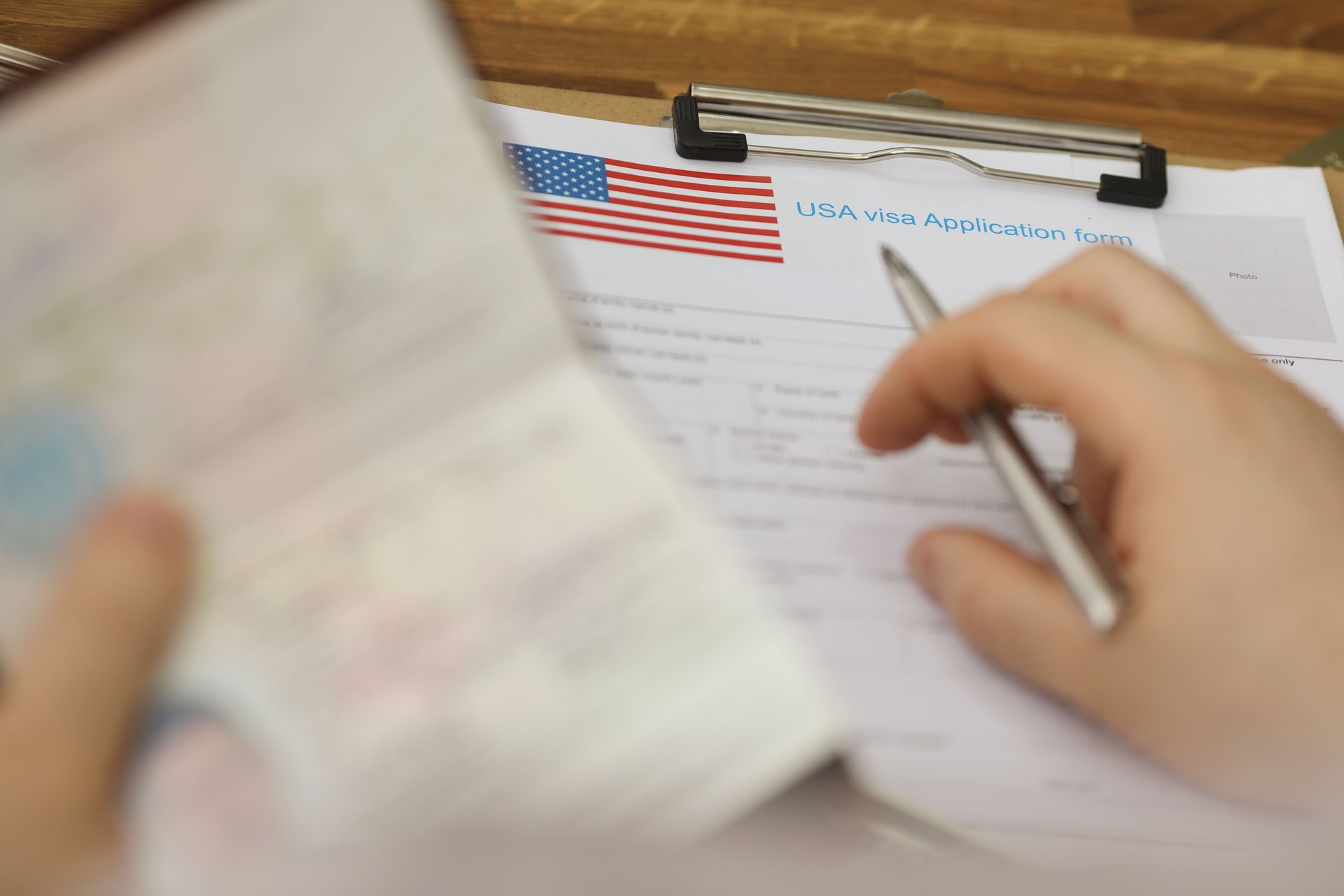 Person filling visa application forms holding personal passport